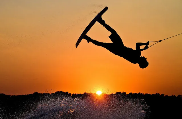 A wakeboarder jumps against the sunset over the Blue Lake in Garbsen in the Region Hannover in Lower Saxony, Germany, 14 September 2016. (Photo by Julia StratenschulteAFP Photo)