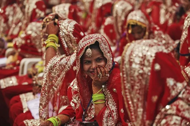An Indian Muslim bride smiles, as she sits with other brides during a mass wedding organized by a social organization in Ahmadabad, India, Sunday, February 15, 2015. Mass weddings in India are organized by social organizations primarily to help families who cannot afford the high ceremony costs as well as the elaborate dowry that is customary in many communities. (Photo by Ajit Solanki/AP Photo)