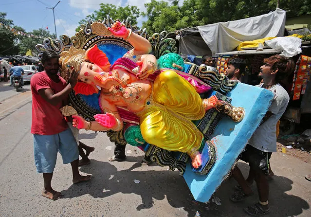 Artisans carry an idol of the Hindu god Ganesh, the deity of prosperity, to load it onto a truck to be transported to a place of worship ahead of the ten-day-long Ganesh Chaturthi festival, in Ahmedabad, India September 11, 2018. (Photo by Amit Dave/Reuters)