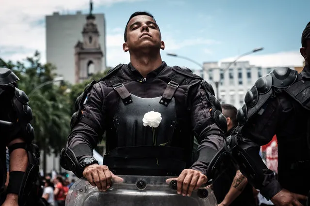 A riot police officer bearing a white flower on his  bulletproof vest takes part in a public servants' protest against austerity measures in front of the Rio de Janeiro state Assembly (ALERJ) in Rio de Janeiro, Brazil, on December 12, 2016. On Monday Rio's lawmakers began voting the measures promoted by the governor Luiz Fernando Pezao pushing budget cuts. (Photo by Yasuyoshi Chiba/AFP Photo)