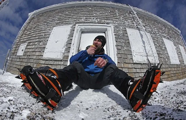 In this Tuesday, March 10, 2015 photo, Nathan Iannuccillo, 23 of Smithfield, R.I., takes a lunch break after climbing more than 4 miles to reach the summit of Mount Washington, New Hampshire. Sharp steel crampons give him traction on the icy trails. (Photo by Robert F. Bukaty/AP Photo)