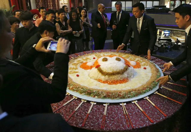 Restaurant employees arrange an 88 kg plate of yusheng or raw fish decorated to mark the year of the monkey before a “lo hei” dinner ahead of the Lunar New Year in Singapore January 8, 2016. Yu sheng is served to raise “good luck” for the new year in a celebration known as “lo hei”, which is Cantonese for “to toss luck”. Participants will toss the shredded ingredients into the air with chopsticks while saying auspicious wishes aloud to mark the start of a prosperous new year. (Photo by Edgar Su/Reuters)