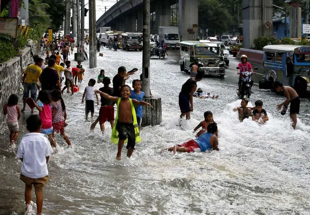 Children play on a flooded boulevard brought about by a busted pipe at low-lying Sta. Mesa district in Manila, Philippines Thursday, February 11, 2016. Thousands of residents were affected by the accident which occurred as the country is still feeling the effects of low water supply due to the El Nino phenomenon. (Photo by Bullit Marquez/AP Photo)