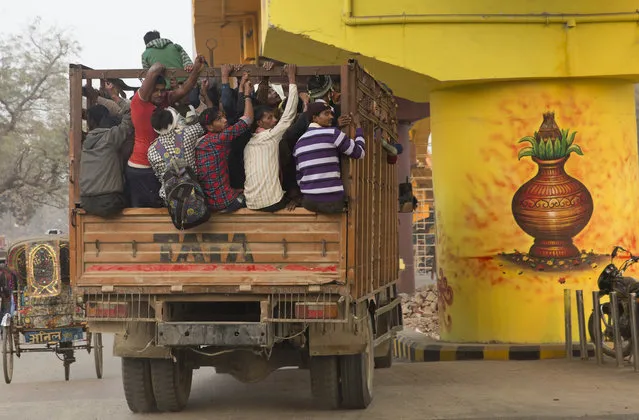 View of Indian villagers returning home on a truck after work besides a flyover pillar, painted as part of the 'Paint My City' project ahead of Kumbh Mela festival in Allahabad, India, Tuesday, December 11, 2018. Kumbh Mela is a 45-days festival starting from January 2019, where millions of Hindu devotees are expected to attend with the belief that taking a dip in the waters of the holy river will cleanse them of their sins. (Photo by Rajesh Kumar Singh/AP Photo)