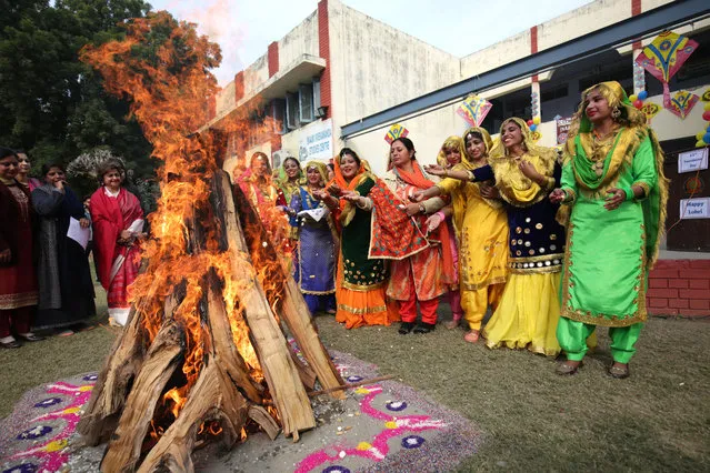 Indian students and teachers wearing traditional Punjabi attire put groundnuts and popcorn into a bonfire as they celebrate Lohri festival at a college in Amritsar, India, 12 January 2019. On the Lohri day people fly kites and light bonfires at night to celebrate the event. Lohri, one of the major festivals of Punjab, marks the culmination of winter and is celebrated in the month of January every year. (Photo by Raminder Pal Singh/EPA/EFE)
