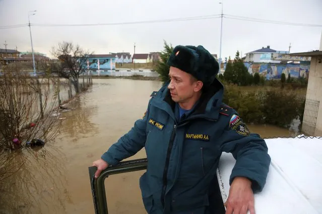 An Emergency Situation Ministry employee looks at a flooded area after a storm near Evpatoria in Crimea, Monday, November 27, 2023. A storm in the Black Sea took down power grids and left almost half a million people without power after it flooded roads, ripped up trees and damaged buildings in Crimea, Russian state news agency Tass said. (Photo by AP Photo)