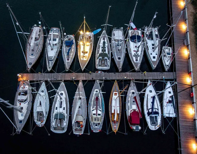Sail boats sit in their slips at a small harbor in Niendorf at the Baltic Sea, Germany, late Saturday, July 24, 2021. (Photo by Michael Probst/AP Photo)
