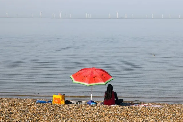A woman sits in the beach on an unseasonably hot day in Herne Bay, Britain on October 8, 2023. (Photo by Kevin Coombs/Reuters)
