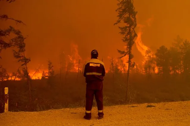 A firefighter stands at the scene of forest fire near Kyuyorelyakh village at Gorny Ulus area west of Yakutsk, in Russia, Saturday, August 7, 2021. Wildfires in Russia's vast Siberia region endangered a dozen villages Saturday and prompted authorities to evacuate some residents. (Photo by Ivan Nikiforov/AP Photo)
