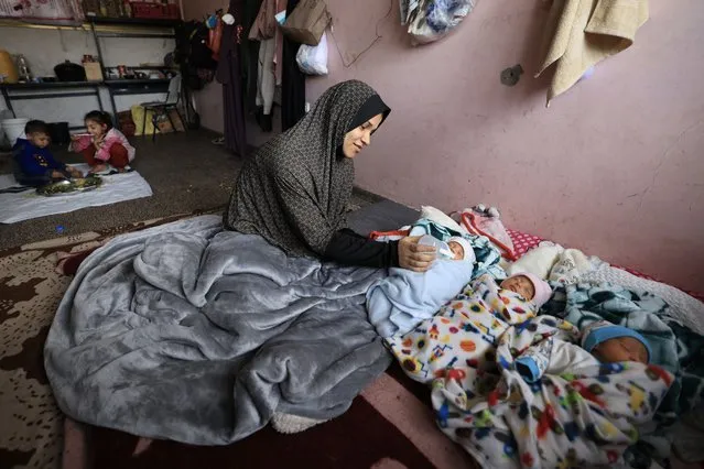 Iman al-Masri, a displaced Palestinian who fled from her home in Beit Hanoun with her family to escape Israeli bombardment, feeds one of her quadruplets - with the fourth still being treated in hospital - as they take shelter at a school in Deir al-Balah in the central Gaza Strip on December 27, 2023, amid continuing battles between Israel and the militant Hamas group. (Photo by Mahmud Hams/AFP Photo)