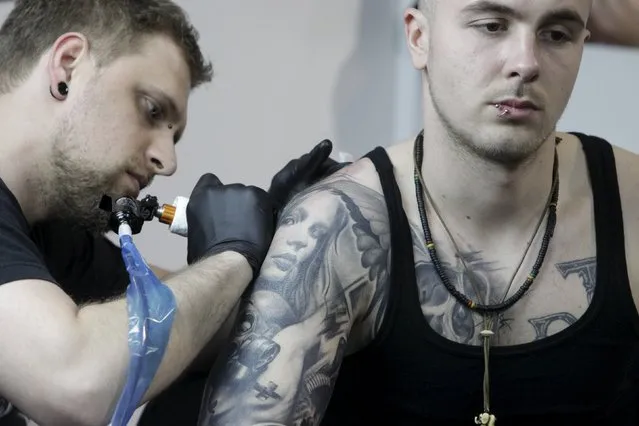 An artist draws a tattoo on a man's shoulder during a tattoo convention in Ljubljana April 18, 2015. (Photo by Srdjan Zivulovic/Reuters)