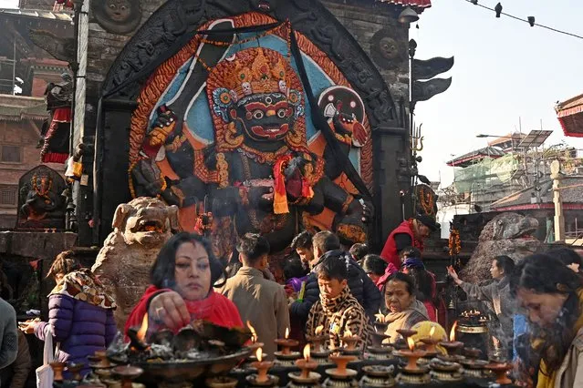 Devotees gather to pray in front of an idol of the Hindu god Kaal Bhairav at Durbar Square in Kathmandu on December 26, 2023. (Photo by Prakash Mathema/AFP Photo)