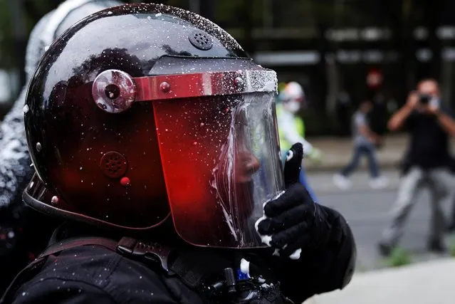 A policeman wipes his helmet after being sprayed on by members of a feminist collective during a protest on International Safe Abortion Day in Mexico City, Mexico on September 28, 2021. (Photo by Toya Sarno Jordan/Reuters)