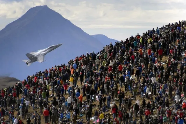 A crowd watches an F/A-18 Hornet fighter aircraft of the Swiss Air Force on October 11, 2012  doing a flight demonstration of the Swiss Air Force over Axalp in the Bernese Oberland. (Photo by Fabrice Coffrini/AFP Photo)