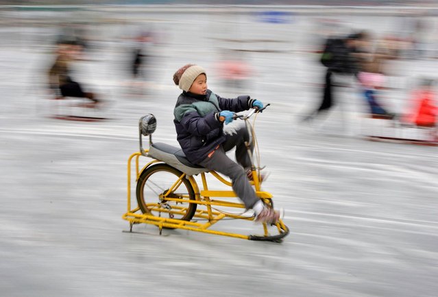 A Chinese boy rides an ice bike on the partially frozen Houhai Lake during the Lunar New Year holiday  in Beijing on February 6, 2014. (Photo by Mark Ralston/AFP Photo)