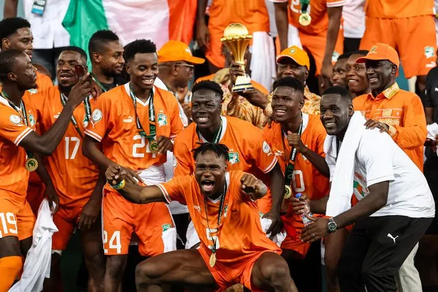 President of Ivory Coast Alassane Ouattara (C) lifts the Africa Cup of Nations trophy on the podium after Ivory Coast won the Africa Cup of Nations (CAN) 2024 final football match between Ivory Coast and Nigeria at Alassane Ouattara Olympic Stadium in Ebimpe, Abidjan on February 11, 2024. (Photo by Franck Fife/AFP Photo)
