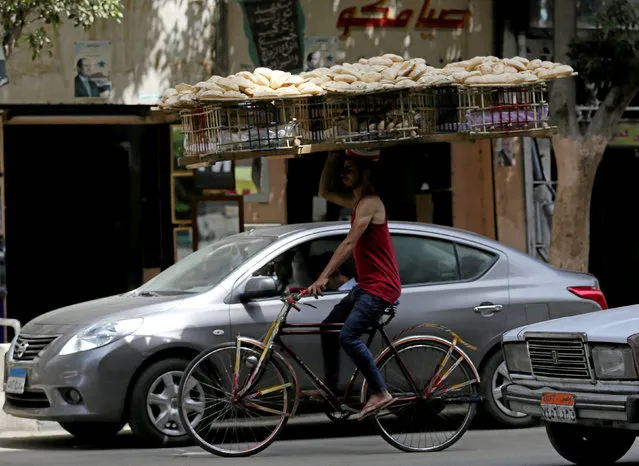 A bakery worker rides a bicycle as he carries fresh bread on his head in Cairo, Egypt, May 10, 2016. (Photo by Mohamed Abd El Ghany/Reuters)