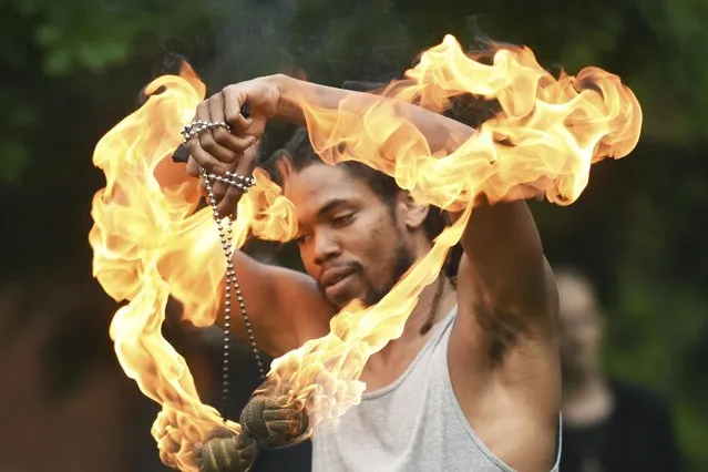 Fire dancer Nick May performs Wednesday, July 7, 2021, in the gardens of the Maud Preston Palenske Memorial Library in St. Joseph, Mich. (Photo by Don Campbell/The Herald-Palladium via AP Photo)