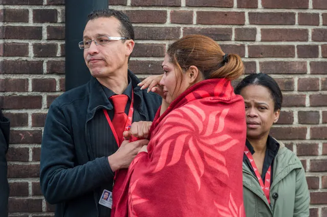 People comfort each other after being evacuated from Brussels airport, after explosions rocked the facility in Brussels, Belgium, Tuesday March 22, 2016. Authorities locked down the Belgian capital on Tuesday after explosions rocked the Brussels airport and subway system, killing at least 13 people and injuring many more. Belgium raised its terror alert to its highest level, diverting arriving planes and trains and ordering people to stay where they were. Airports across Europe tightened security. (Photo by Geert Vanden Wijngaert/AP Photo)
