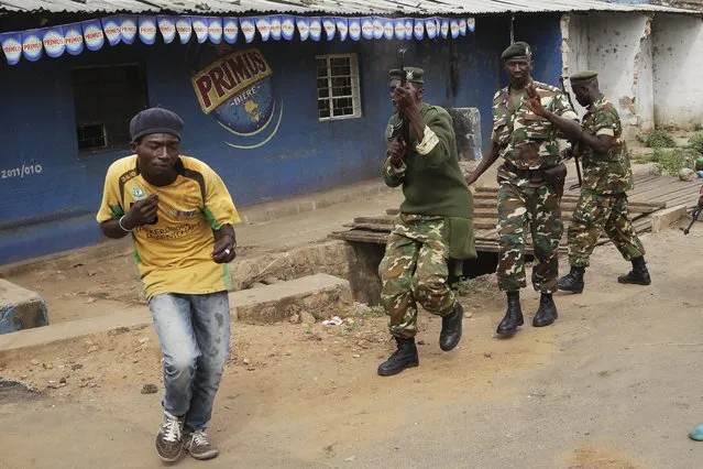 Demonstrators duck and run from soldiers firing into the air to disperse a crowd of demonstrators who had cornered  Jean Claude Niyonzima a suspected member of the ruling party's Imbonerakure youth militia in a sewer in the Cibitoke district of Bujumbura, Burundi, Thursday May 7, 2015. (Photo by Jerome Delay/AP Photo)