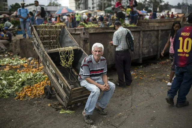 A man who hauls vegetables rests on his cart during a break, at the Coche Market in Caracas, Venezuela, Thursday, May 2, 2019. In its narrow pathways, bare chested workers push carts heavy with sacks of onions and potatoes, vying for space with shoppers and vendors selling cigarettes and bottled water. (Photo by Rodrigo Abd/AP Photo)