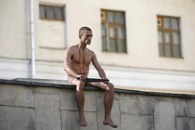 Artist Pyotr Pavlensky sits on the wall enclosing the Serbsky State Scientific Center for Social and Forensic Psychiatry after he cut off a part of his earlobe during his protest action titled “Segregation” in Moscow, Russia, October 19, 2014. (Photo by Maxim Zmeyev/Reuters)