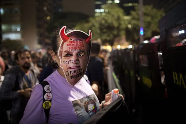 A woman wears a retouched mask with the image of Brazil's President Jair Bolsonaro during a protest against education cuts in Sao Paulo, Brazil, Thursday, May 23, 2019. A few hundred students demonstrated in Rio de Janeiro and Sao Paulo to protest big cuts in federal funding for the public education network by President Jair Bolsonaro. (Photo by Victor R. Caivano/AP Photo)