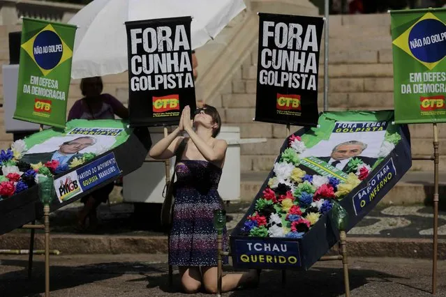 A supporter of President Dilma Rousseff kneels and gestures between mock coffins with the portrait of Vice-President Michel Temer, during a demonstration against the impeachment of Rousseff, in Porto Alegre, Brazil, April 17, 2016. (Photo by Lunae Parracho/Reuters)