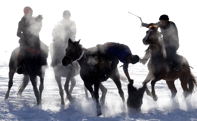 Kyrgyz horsemen take part in the traditional Central Asian sport Kok-Boru, dragging a goat, in the village of Gornaya Mayevka, 30 km from Bishkek, Kyrgyzstan, 12 January 2023. Kok-boru is a traditional Central Asian game in which players grab a goat carcass from the ground, riding horses and trying to score a goal by putting it in the opponent's goal. (Photo by Igor Kovalenko/EPA/EFE)