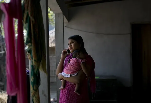 Meghla talks on the phone as she holds her 2 month old baby on March 7, 2017 in Khulna division, Bangladesh.  17-year-old Meghla married her 30-year-old husband, Liton, during an arranged marriage in 2015, while she was 15. (Photo by Allison Joyce/Getty Images)