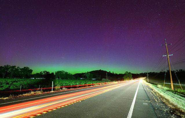 A shooting star streaks over the northern lights also known as the aurora borealis along a highway north of San Francisco in Middletown, California on May 11, 2024. (Photo by Josh Edelson/AFP Photo)