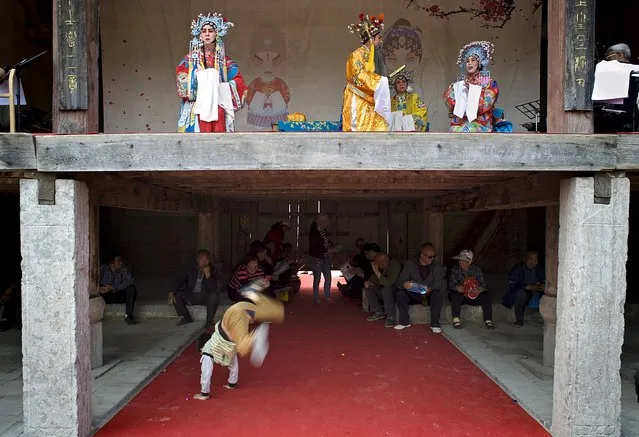 Performers play local opera on stage while people sit and a boy plays under the stage in Wanrong county, Shanxi Province, China, April 24, 2016. (Photo by Reuters/China Daily)