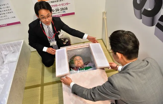 A woman lies in a coffin at a funeral fair in the Grand Generation's Collection 2014 produced by Japanese retailer Aeon in Makuhari on April 11, 2014.  The three-day collection will be held until April 13. (Photo by Kazuhiro Nogi/AFP Photo)