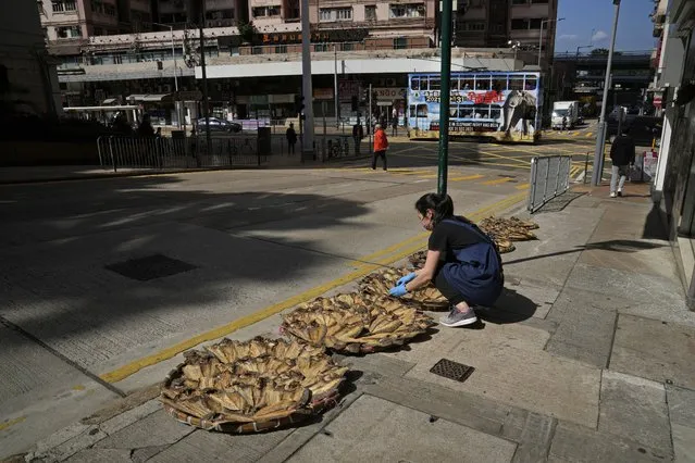 A woman wearing face mask, places dried fishes on a street in Hong Kong, Friday, February 11, 2022. Hong Kong residents expressed growing frustration this week after new, tighter coronavirus restrictions went into effect, imposed by city leaders in line with Beijing's zero-COVID policy. (Photo by Kin Cheung/AP Photo)