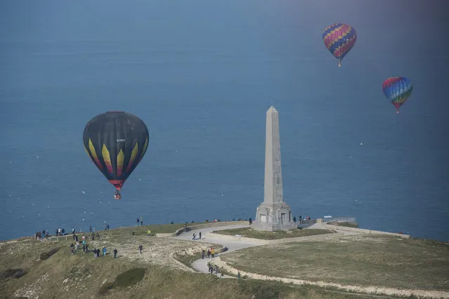 Three  of the 100 balloons taking part in a World Record attempt for a mass hot air balloon crossing of the English Channel, pass the Dover Patrol Monument near Calais in northern France Friday April 7, 2017. (Photo by Victoria Jones/PA Wire via AP Photo)