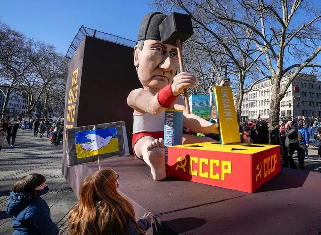 A satirical carnival float depicts Russia's President Vladimir Putin playing with the Ukraine to restore the Soviet Union on a square in Cologne, Germany, during a peace march against the war in Ukraine on Shrove Monday, February 28, 2022. The traditional carnival Rose Monday Parade in Cologne was cancelled due to Russia's war in Ukraine. Instead of the parade, the political carnival floats were placed in the city followed by a peace protest of revelers. (Photo by Martin Meissner/AP Photo)