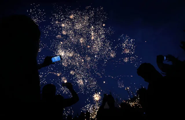 Iraqi Kurds watch as fireworks light the sky in the town of Akra, 500 km north of Baghdad, on March 20, 2017 during the Noruz spring festival celebrations. The Persian New Year is an ancient Zoroastrian tradition celebrated by Iranians and Kurds which coincides with the vernal (spring) equinox and is calculated by the solar calender. (Photo by Safin Hamed/AFP Photo)