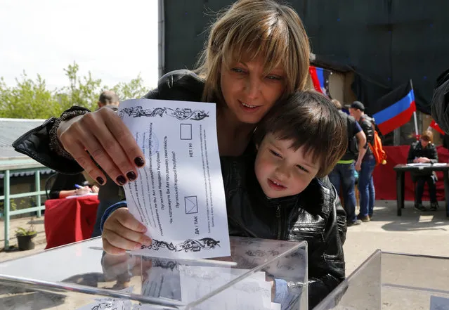 An Ukrainian woman and her son, who are in Russia at the moment, cast a referendum ballot in Moscow, Russia, on Sunday, May 11, 2014. Residents of two restive regions in eastern Ukraine cast ballots Sunday in referendums, which seek approval for declaring sovereign people's republics in the Donetsk and Luhansk regions. Many of Ukrainians living in Moscow came to vote as well. (Photo by Dmitry Lovetsky/AP Photo)