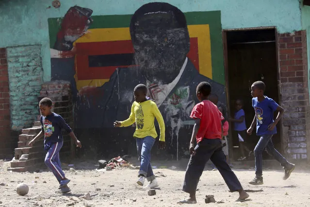 Children play soccer next to a defaced portrait of Former Zimbabwean President Robert Mugabe in Harare, Friday, September 6 2019. Robert Mugabe, the former leader of Zimbabwe forced to resign in 2017 after a 37-year rule whose early promise was eroded by economic turmoil, disputed elections and human rights violations, has died. He was 95. (Photo by Tsvangirayi Mukwazhi/AP Photo)