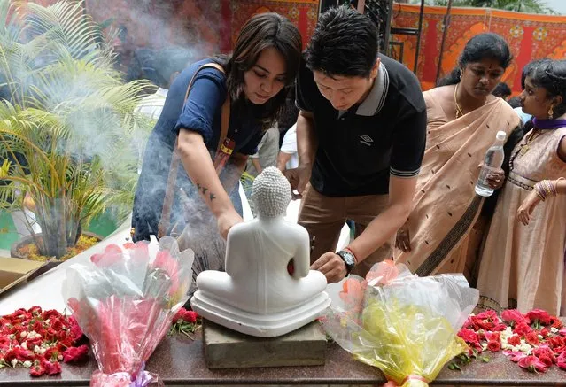 Indian Buddhist devotees leave offerings and offer prayers at a statue of the Buddha during celebrations to mark Buddha Purnima at the Maha Bodhi Society in Bangalore on May 10, 2017. The Buddha was born in Lumbini, Nepal and devotees commemorate his birth, his attaining enlightenment and his passing away on the full moon day of May, which this year falls on May 10. (Photo by Manjunath Kiran/AFP Photo)