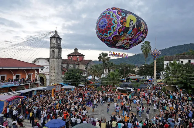People watch a “Cantoya” balloon, during the International Festival of Paper Artistic Balloons 2019, in Tuzamapan, Puebla, Mexic​o, 17 November 2019. (Photo by Hilda Ríos/EPA/EFE)