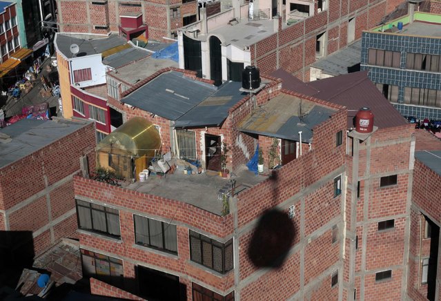 The shadow of a cable car falls on a building as it travels past, in the Chijini district of La Paz, July 23, 2015. (Photo by David Mercado/Reuters)