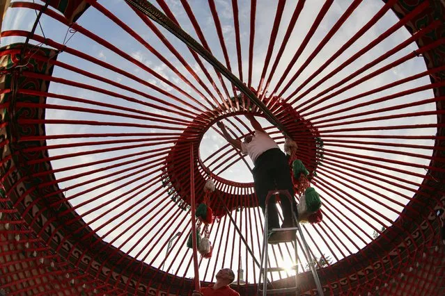 Kyrgyz men assemble a yurt preparing for the World Festival of Epics of the World on the central square of Bishkek, Kyrgyzstan, 22 September 2021. The cultural festival runs from 23 to 26 September. The yurt is traditional round tent used by the nomads in Central Asian steppes, consists of a wooden frame covered with felt or skins. (Photo by Igor Kovalenko/EPA/EFE)