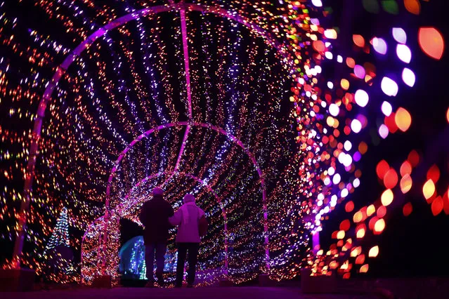 A couple walks through a tunnel of light during the annual Garden Glow at Missouri Botanical Garden Tuesday, December 3, 2019, in St. Louis. The annual event, which runs through Jan. 4, 2020, transforms the garden into a nightly winter wonderland of light and holiday music. (Photo by Jeff Roberson/AP Photo)