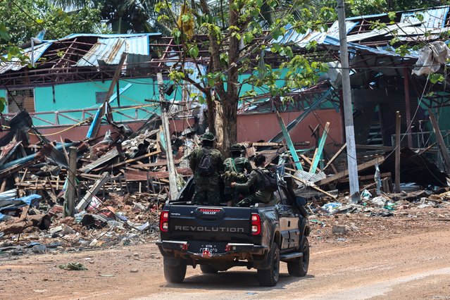 Soldiers from the Karen National Liberation Army (KNLA) patrol on a vehicle, next to an area destroyed by Myanmar's airstrike in Myawaddy, the Thailand-Myanmar border town under the control of a coalition of rebel forces led by the Karen National Union, in Myanmar, on April 15, 2024. (Photo by Athit Perawongmetha/Reuters)