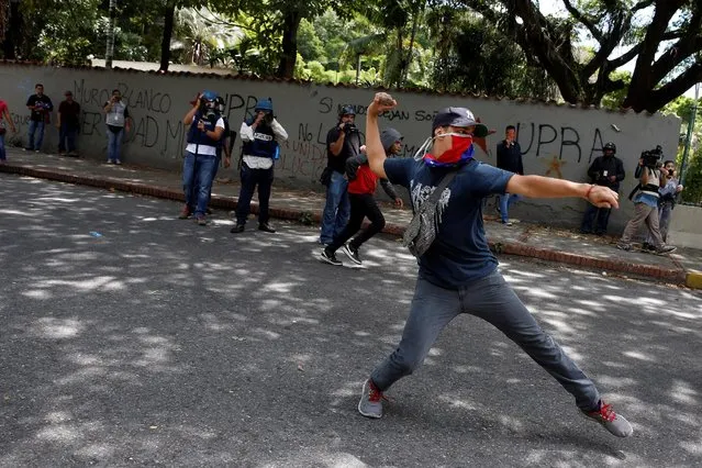A demonstrator attempts to throw a stone towards riot police officers during a protest called by university students against Venezuela's government in Caracas, Venezuela, June 9, 2016. (Photo by Carlos Garcia Rawlins/Reuters)