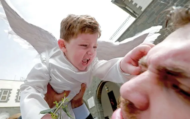 A toddler in angel costume pinches a man as Catholic believers gather outside Zaiton Church to mark Palm Sunday in the capital Damascus in Bab Sharki, Old Damascus on April 14, 2019. (Photo by Louai Beshara/AFP Photo)