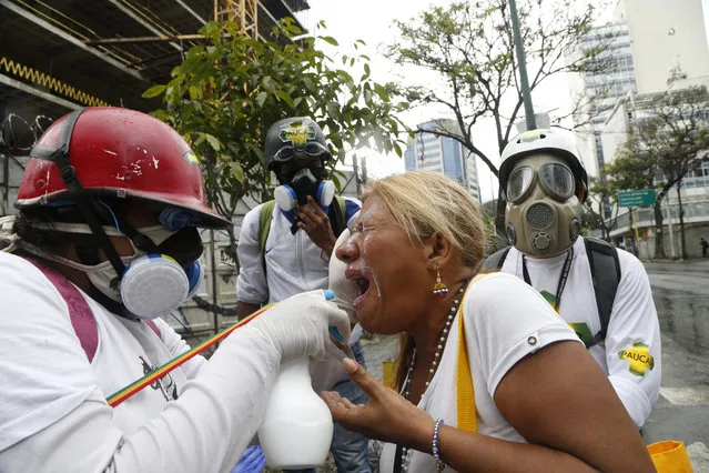 Medics assist a woman who was affected by tear gas during protests in Caracas, Venezuela, Thursday, June 29, 2017. Demonstrators are taking the the streets after three months of continued protests that has seen the country's chief prosecutor Luisa Ortega barred from leaving the country and her bank accounts frozen, by the Supreme Court following her mounting criticisms of President Nicolas Maduro. (Photo by Ariana Cubillos/AP Photo)