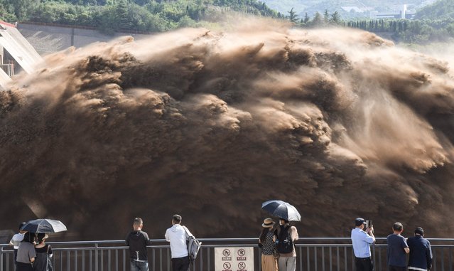 People watch water and sand being released from the Xiaolangdi Reservoir Dam in Jiyuan, in China's central Henan province on July 7, 2023. (Photo by AFP Photo/China Stringer Network)