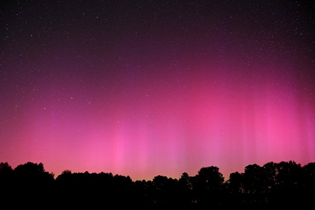 This long exposure picture shows the northern lights (aurora borealis) illuminating the sky above the field in the village of Wigry, Suwalki region, during the annual Perseids meteor shower early on August 12, 2024. (Photo by Sergei Gapon/AFP Photo)